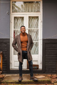 Full length portrait of man standing against building