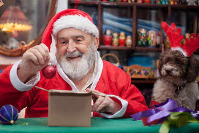 Senior man in santa claus costume sitting at home