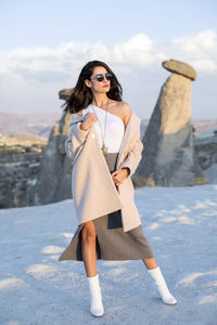 Full length of woman wearing sunglasses while standing in snow