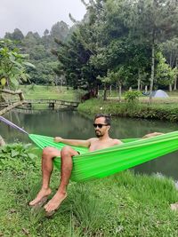 Man sitting by lake against trees