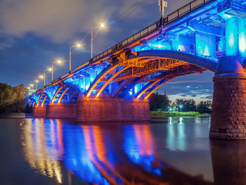 Illuminated bridge over river at night