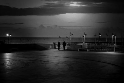 Silhouette pier on sea against sky at dusk