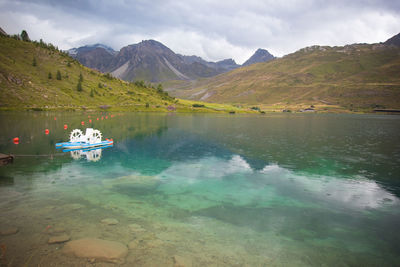 Tignes lake in the alps with pedal boats under a storm