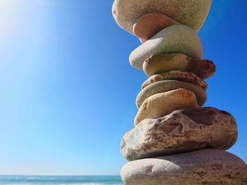 Close-up of stone stack on rock by sea against clear sky