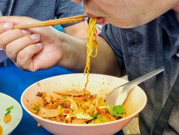 Midsection of man eating noodles with chopsticks