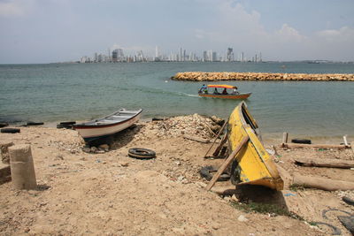 Boats moored on sea by city against sky