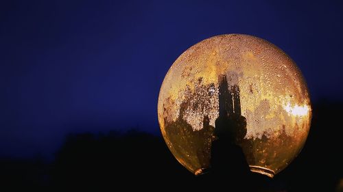 Close-up of illuminated lighting equipment against clear sky at night