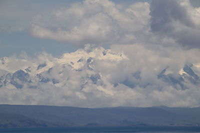 Scenic view of clouds over land and mountains against sky