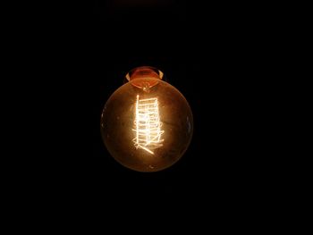 Close-up of illuminated light bulb against black background