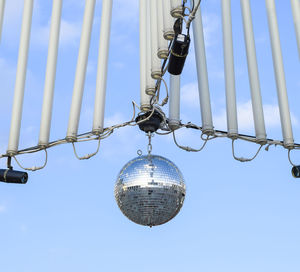 Low angle view of disco ball hanging against sky