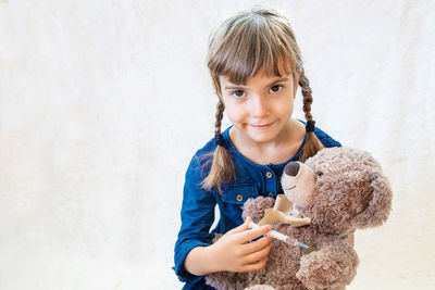 Girl with teddy bear holding syringe