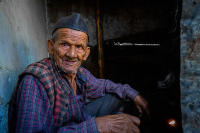 Close-up portrait of senior man sitting in abandoned house