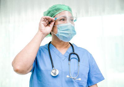 Portrait of female doctor wearing mask against white background