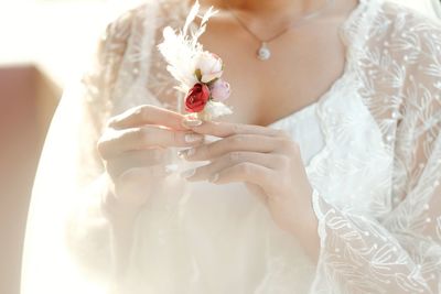 Midsection of woman holding white flower bouquet