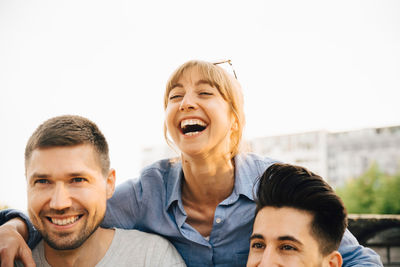 Mid adult woman laughing while standing by male friends at social gathering
