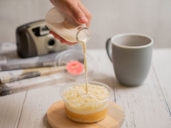 Close-up of hand pouring milk on to the milk bath  cheese dessert