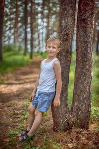 Portrait of smiling girl on tree trunk in forest