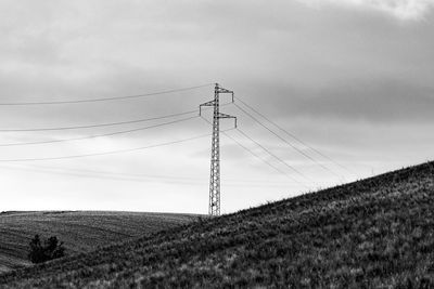 Electricity pylon on field against sky