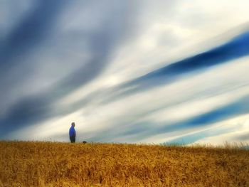 Rear view of woman standing on field against sky