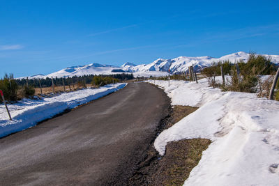 Snow covered landscape against blue sky