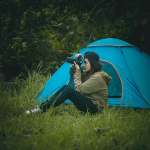 Rear view of woman sitting on grass in field