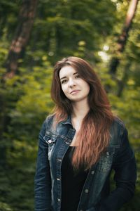 Portrait of smiling young woman standing in forest