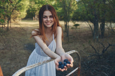 Portrait of smiling young woman against trees