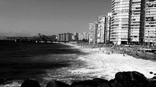 Sea by cityscape against clear sky