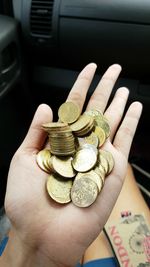 High angle view of cropped hand showing various coins in car