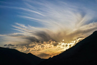 Low angle view of silhouette mountains against dramatic sky