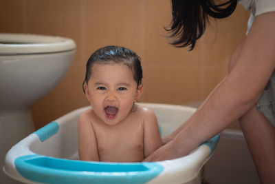 Portrait of shirtless girl sitting in bathroom at home