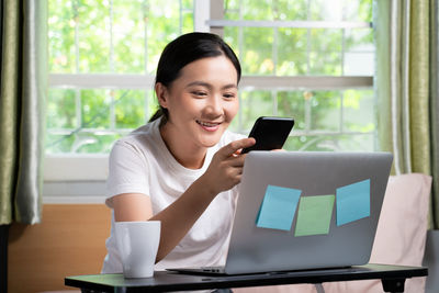 Mid adult man using mobile phone while standing on table