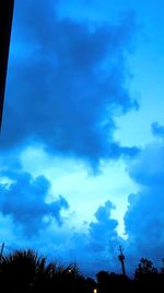 Low angle view of silhouette trees against blue sky