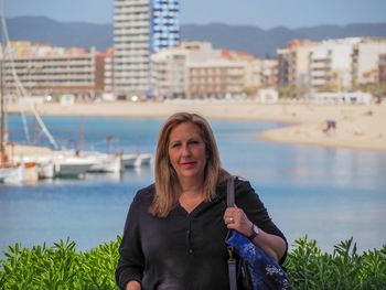 Portrait of woman standing against river in city