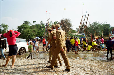 Rear view of people walking in park against sky