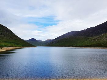 Scenic view of lake by mountains against sky