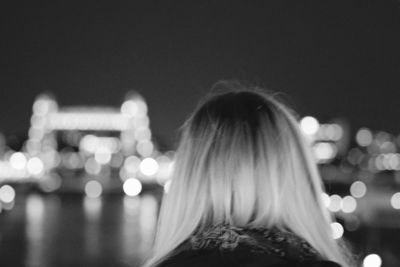 Rear view of woman with blond hair at night