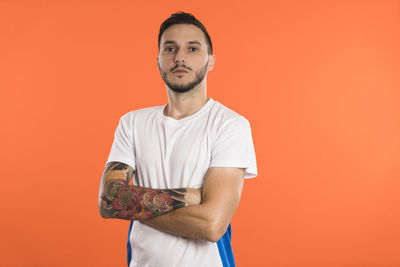 Portrait of young man holding pumpkin against yellow background