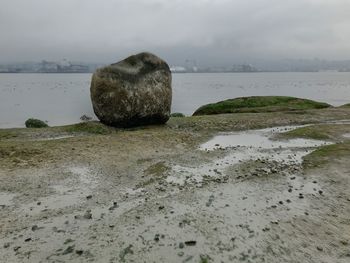 Rocks on shore by sea against sky