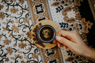 Directly above shot of hand holding coffee cup