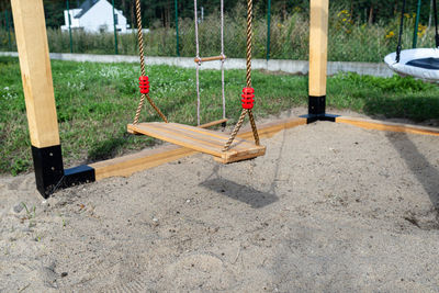 A modern cubic playground made of wooden logs and metal corners, a visible rocker and a nest.