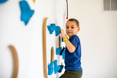 Portrait of boy standing against wall