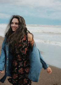 Thoughtful happy young woman walking at beach