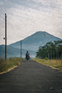 Rear view of people riding motorcycle on road