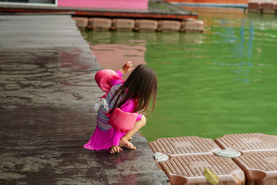 Rear view of woman with pink umbrella on lake