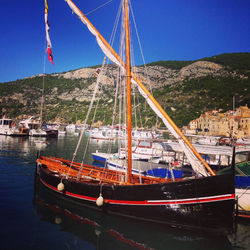 Boats in harbor against mountain