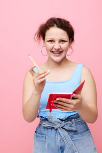 Portrait of young woman using mobile phone against yellow background