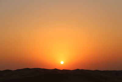 Scenic view of landscape against orange sky