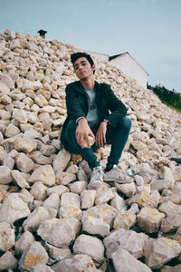 Low angle view of man sitting on rock