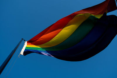 Low angle view of flag against clear blue sky